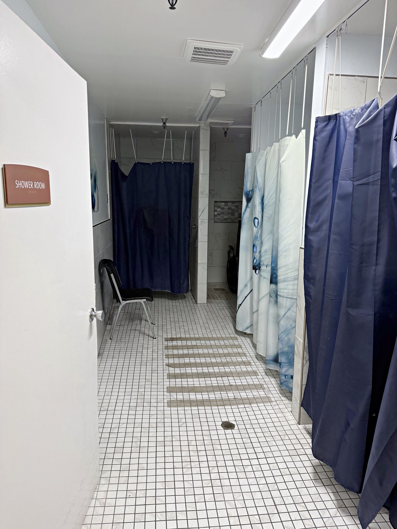 The shower room, with private curtained stalls and a shower chair